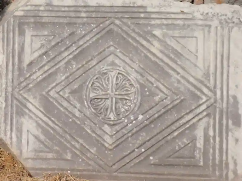 Christian cross with rays inside circle and diamond on what appears to be marble block. Perhaps used as a tombstone. 